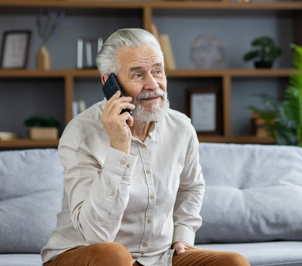 An older man at home, talking on his phone