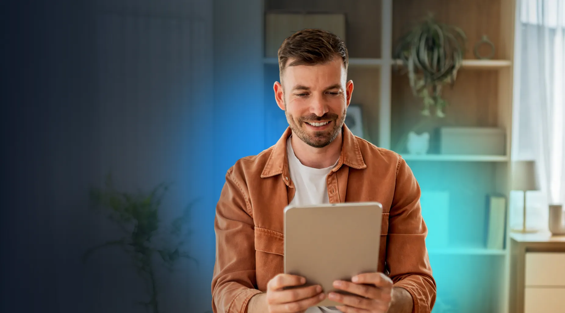 A man at home, smiling at a tablet