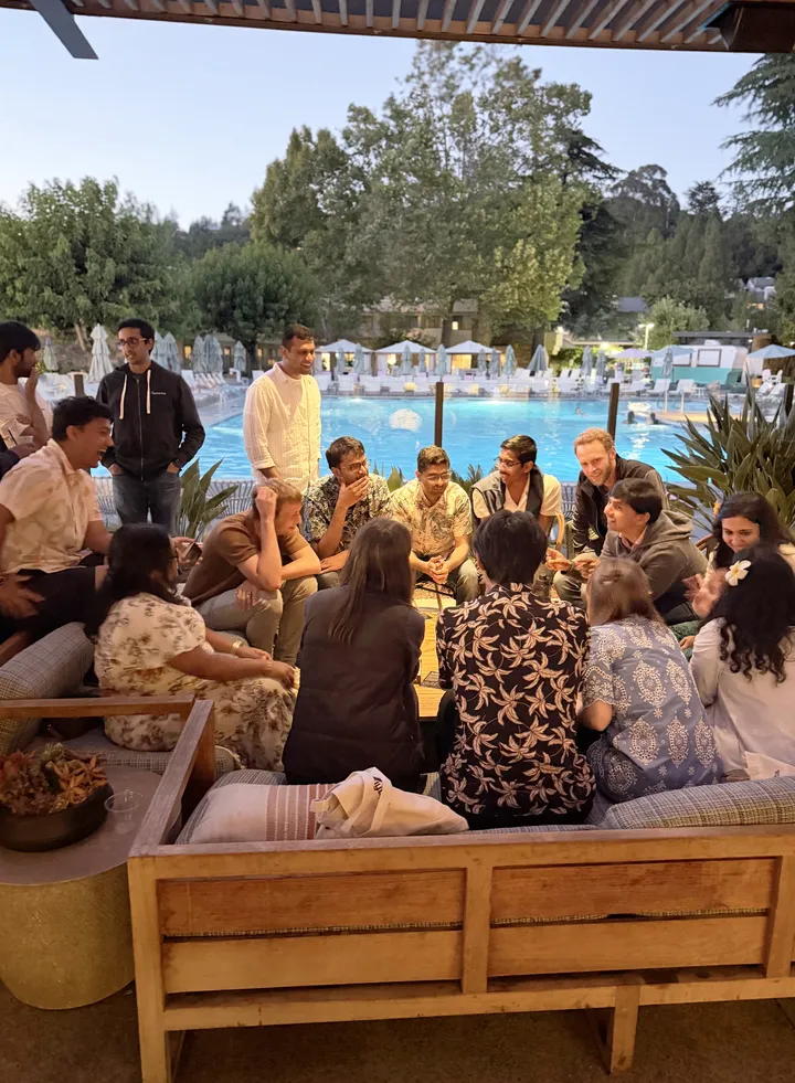 Colleagues talking around a poolside table at an evening team event