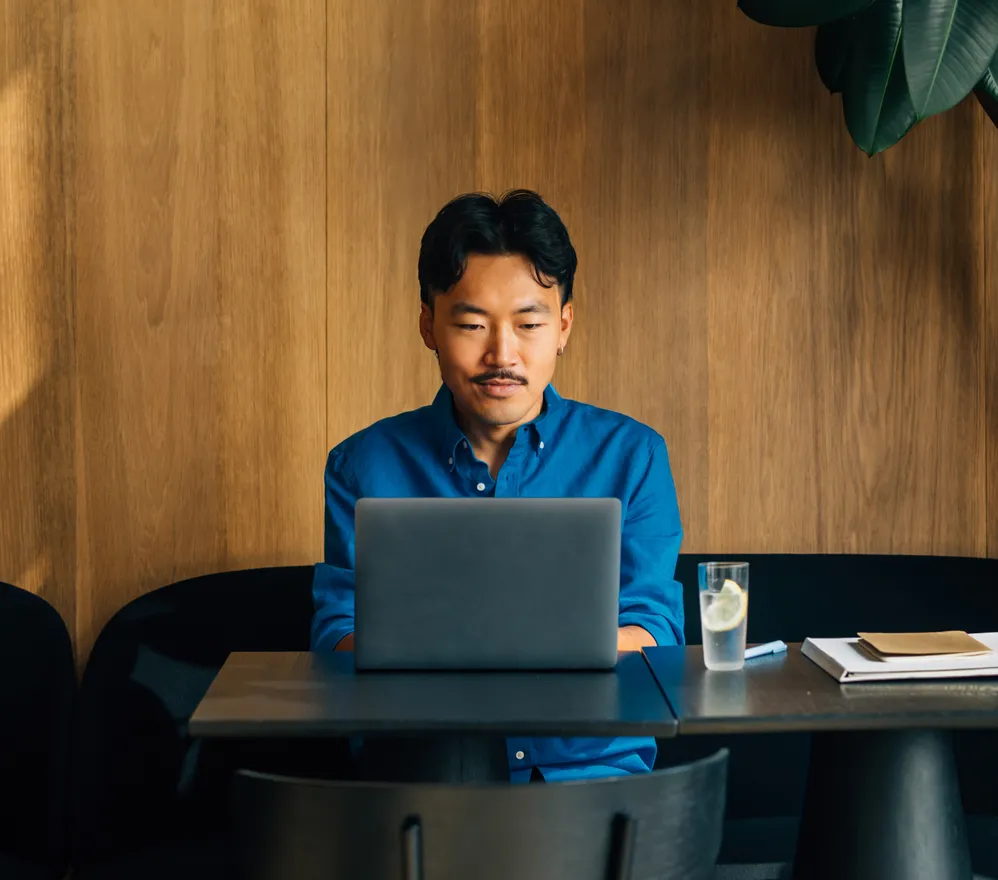 A man working alone on a laptop in a quiet wood-panelled booth