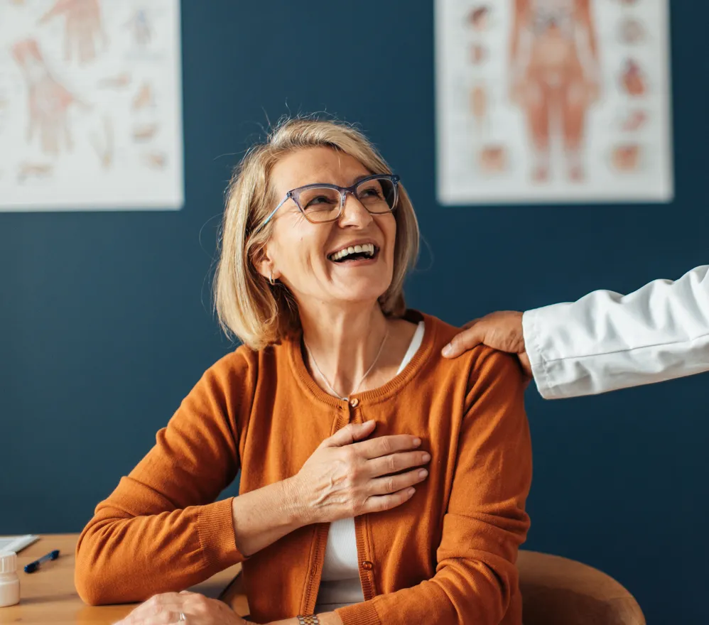 A patient laughing during a consultation as her clinician rests a hand on her shoulder