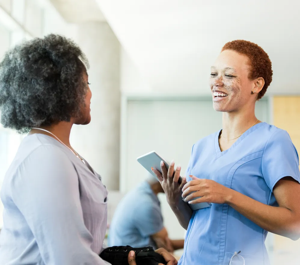 A nurse and a patient talking and smiling in a hospital corridor