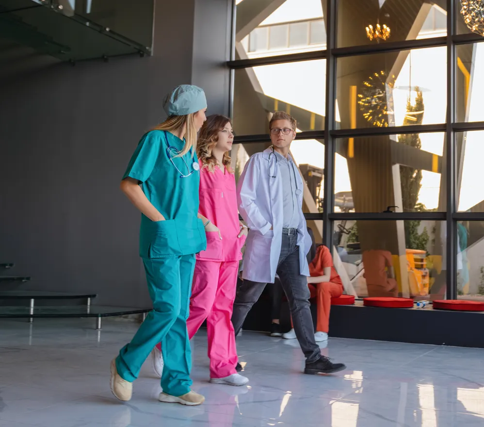 Three clinicians walking together through a bright hospital lobby