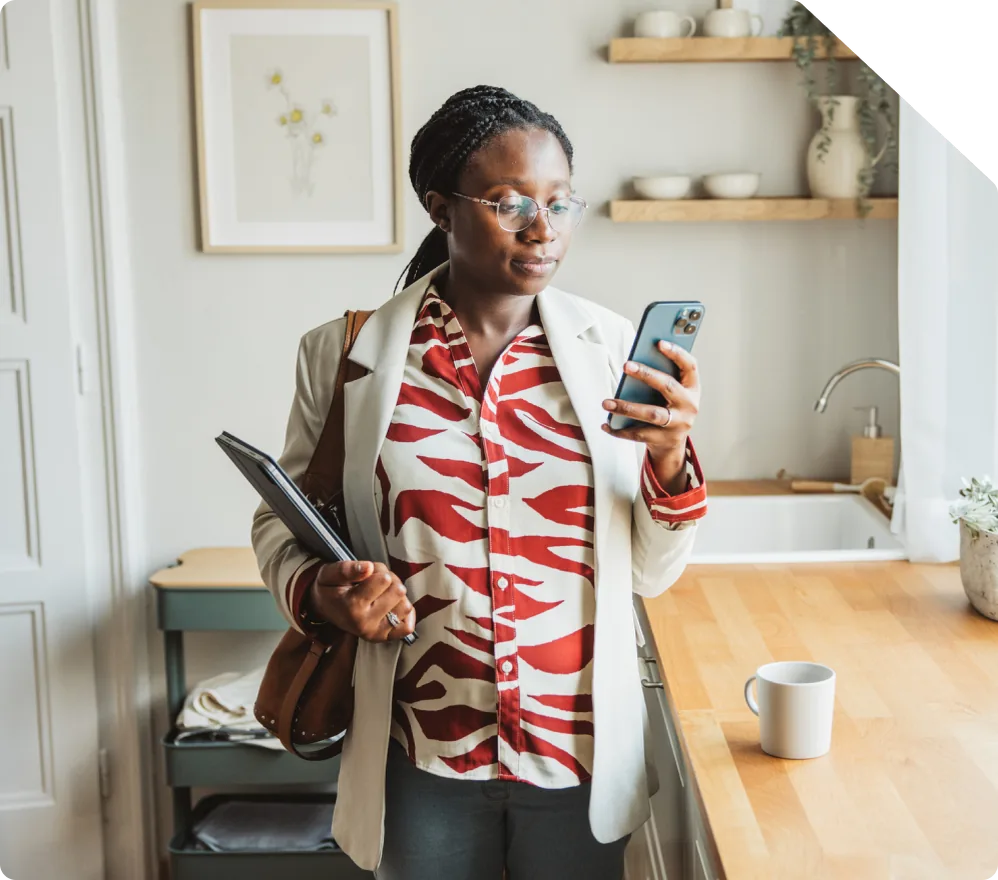 A woman standing in her kitchen looking at her phone