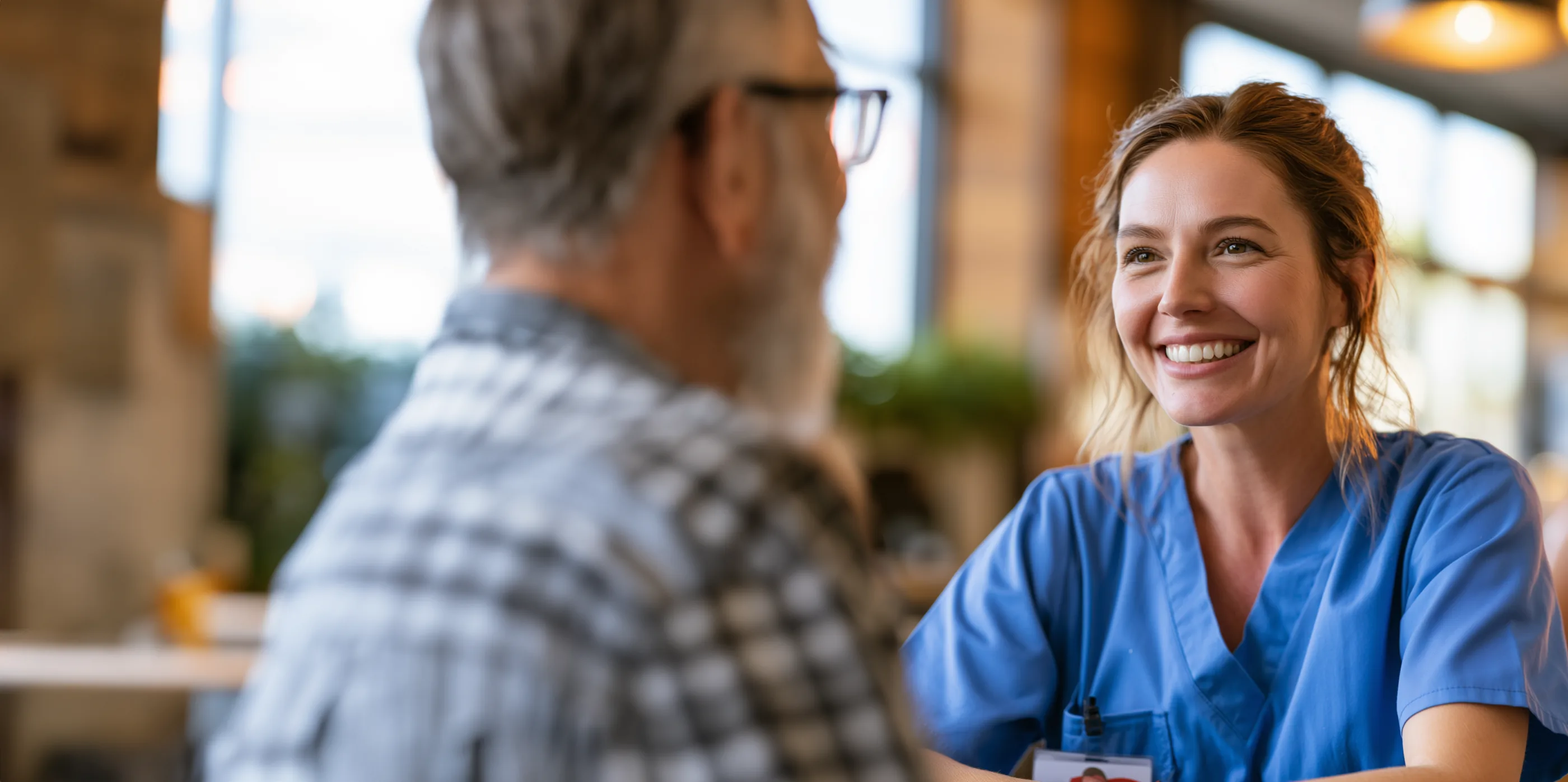 A clinician in scrubs smiling during a conversation with a patient