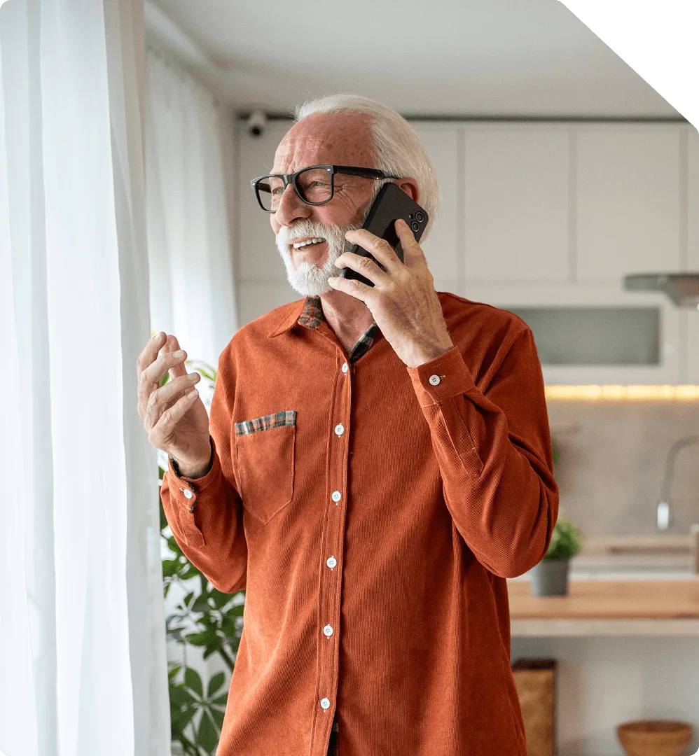 An older man talking on the phone at home