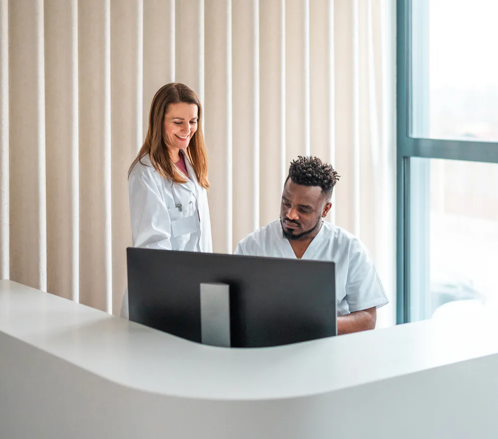 Two care team members reviewing conversation insights on a monitor at a front desk