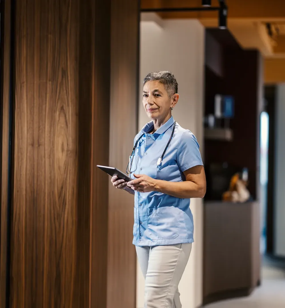 A nurse walking through a clinic with a tablet in hand