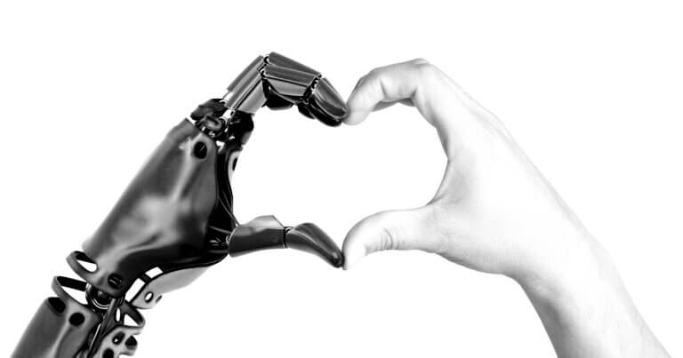 A robot hand and a human hand together forming the shape of a heart