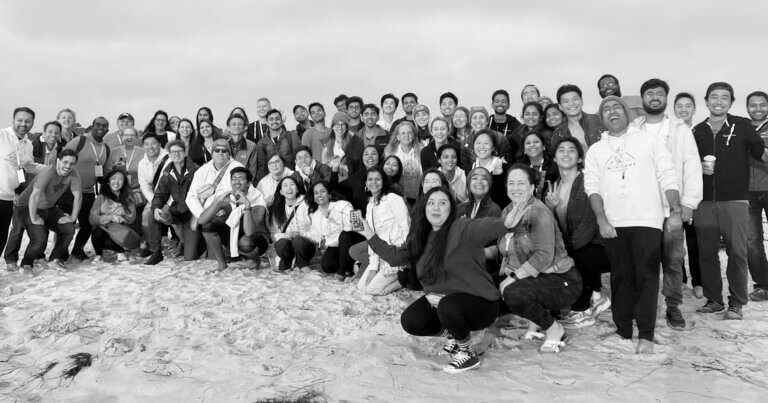 A black-and-white group photo of the Infinitus team at an off-site event.